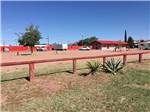 Wooden fence with RV sites and main building in background at WILD WEST RV PARK - thumbnail