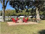 Red Adirondack chairs arrayed around a fire pit at GAINESVILLE RV PARK - thumbnail