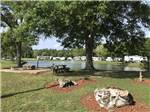 Picnic area with pond and RVs on opposite bank at GAINESVILLE RV PARK - thumbnail