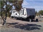 A travel trailer in a gravel RV site at MEADVIEW RV PARK & COZY CABINS - thumbnail