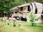 Fifth wheel with picnic table and potted flowers at Cypress Landing RV Park - thumbnail