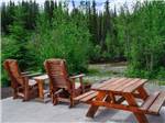 Chairs and a bench on a patio looking at the river at RANCH HOUSE LODGE & RV CAMPING - thumbnail