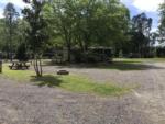 A gravel RV site with a fire pit and bench at OKEFENOKEE PASTIMES CABINS & CAMPGROUND - thumbnail