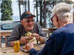 A couple eating food at a picnic table at SHELTER COVE RESORT AND MARINA - thumbnail