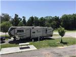 View larger image of A 5th wheel trailer parked in a gravel site at LIGHTHOUSE LANDING RV PARK  CABINS image #2