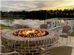 A brick fire pit blazes with serene lake in the background at CREEKFIRE RESORT - thumbnail