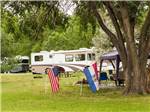 A parked Class-A RV and flags in the grass at The Oaks at Zephyrhills - thumbnail