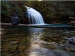 A man sitting in the water looking at a waterfall at SPRING CITY RV PARK - thumbnail
