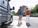 A couple standing by their Class B trailer at WIND CREEK ATMORE CASINO RV PARK - thumbnail