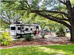 A truck and trailer parked under a tree at SPLASH! RV RESORT & WATERPARK - thumbnail