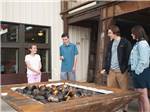 View larger image of People standing around a modern fire pit at IRON SPRINGS ADVENTURE RESORT image #10
