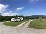 Travel trailer camped in roomy site with mountains in background at CHEWING BLACK BONES CAMPGROUND - thumbnail