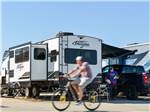 A guy on a bike passing by a parked trailer at COTA CAMPING-PREMIUM RV PARK - thumbnail