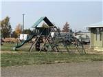 View larger image of Playground with campers in background at STARGAZERS RV RESORT image #5