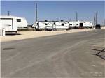 Two travel trailers on dirt sites along paved road at PARK PLACE RV RESORT - thumbnail