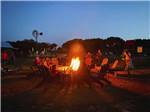 People sitting around a fire pit at dusk at DINOSAUR VALLEY RV PARK - thumbnail
