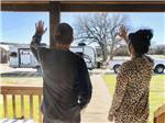 A couple waving at a travel trailer at DINOSAUR VALLEY RV PARK - thumbnail