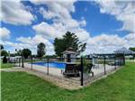 View of pool under blue and clouded sky at OUTPOST RV PARK & CAMPGROUND - thumbnail
