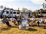 View larger image of Adults sitting around campfire with motorhomes at THE OAKS FAMILY CAMPGROUND image #3