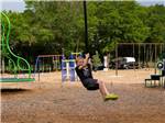 View larger image of Young boy swinging from rope in playground at THE OAKS FAMILY CAMPGROUND image #6