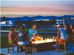 Campers gathered around a fire pit at dusk  at CANYON VIEW RV RESORT - thumbnail