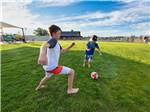 Two kids playing soccer on expansive grass field at CANYON VIEW RV RESORT - thumbnail