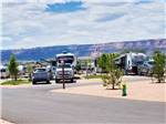 Campsites with rock bluffs looming on the horizon at CANYON VIEW RV RESORT - thumbnail