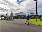 Teen on a scooter riding in front of the office at CHAMPIONS RUN LUXURY RV RESORT - thumbnail