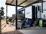 A couple sitting in front of their parked RV at Jetstream RV Resort at Stone Oak Ranch - thumbnail