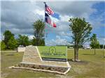 View larger image of Welcome sign and flags at entrance at HIDDEN GROVE RV RESORT image #1