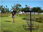 View larger image of A man throwing a fisbee playing disc golf at QUILLYS BIG FISH RV PARK image #8