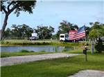 View larger image of An American flag next to an RV site at QUILLYS BIG FISH RV PARK image #11