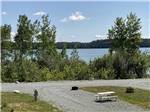 Picnic table and RV site with West Bay in the distance at WEST BAY ACADIA RV CAMPGROUND - thumbnail