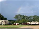 View larger image of Rainbow arcs over campground with tall trees at BANDERA CROSSING RIVERFRONT RV PARK image #3