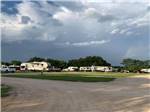 View larger image of RVs on green campground with trees in background at BANDERA CROSSING RIVERFRONT RV PARK image #4