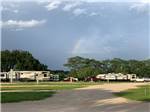 View larger image of RVs on sites separated by greenbelts with rainbow in sky at BANDERA CROSSING RIVERFRONT RV PARK image #5