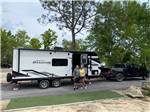 A couple standing in front of their travel trailer at BIG RIG FRIENDLY RV RESORT - thumbnail