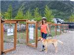 A woman takes her dog to the pet area at ALPINE VALLEY RV RESORT - thumbnail