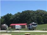 RVs camped with building covered by red roof in background at CROWS NEST RV RESORT - thumbnail