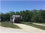 Rushmore fifth-wheel parked in site with patio chairs at CROWS NEST RV RESORT - thumbnail