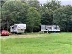 A car and two trailers parked in a grassy area at DREAMLAND RV PARKS - thumbnail