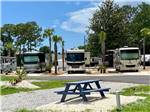 A row of motorhomes parked in gravel sites at SOWAL PALMS RV PARK - thumbnail
