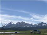 A tipi being built with mountains in the distance at Buffalo Calf Campground - thumbnail