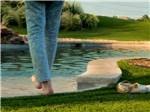 A man putting his foot in the swimming pool at BUDA PLACE RV RESORT - thumbnail