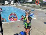 A small boy standing by the pool with a mask and snorkel at BUTTON'S FAMILY CAMPGROUND - thumbnail