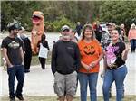 A group of people standing around with a T-Rex sneaking up behind them at BUTTON'S FAMILY CAMPGROUND - thumbnail