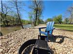 A blue chair and fire pit near the creek at BULL CREEK RV PARK - thumbnail