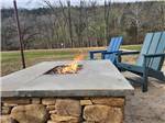 A fire pit burning next to two chairs at BULL CREEK RV PARK - thumbnail