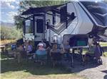 A group of people sitting around a fifth wheel trailer at WHITE KNOB MOTEL & RV PARK - thumbnail