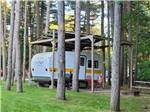 Trailer parked in a shaded site at ELKHART RV RESORT BY RJOURNEY - thumbnail